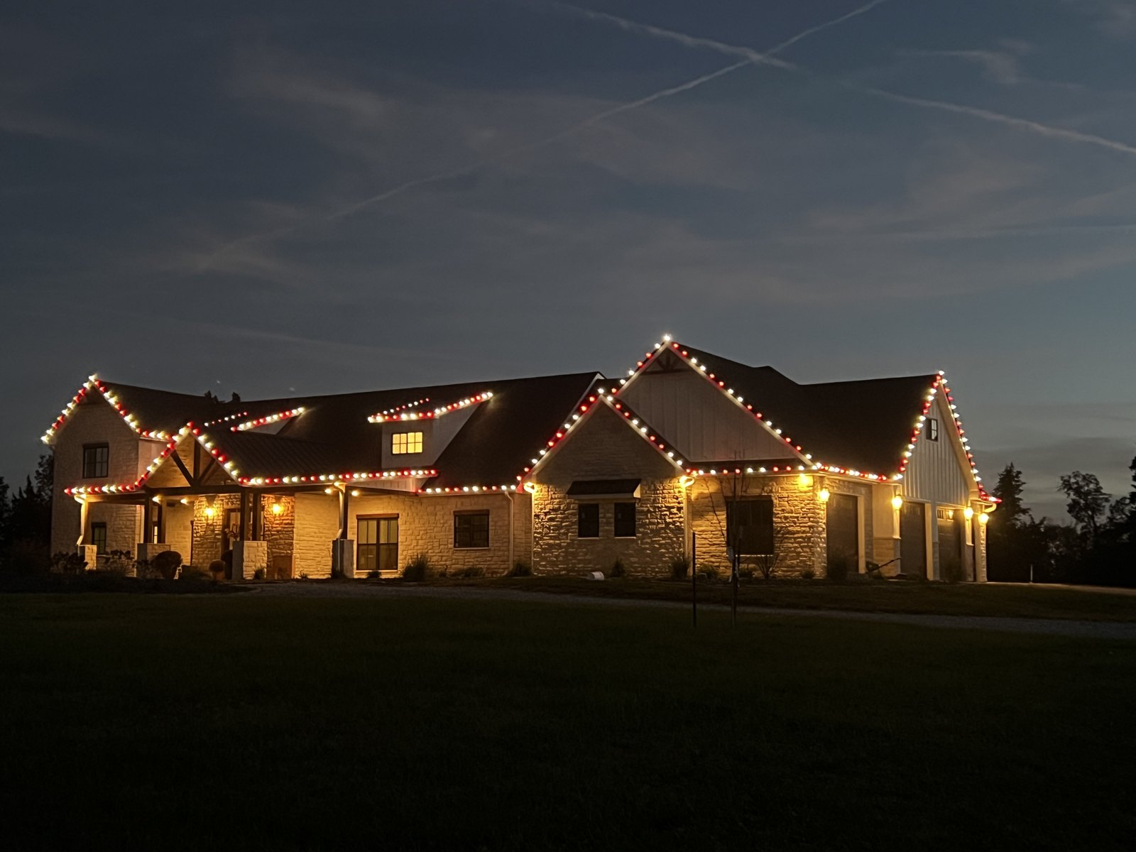Warm white roofline lights across a large home at night