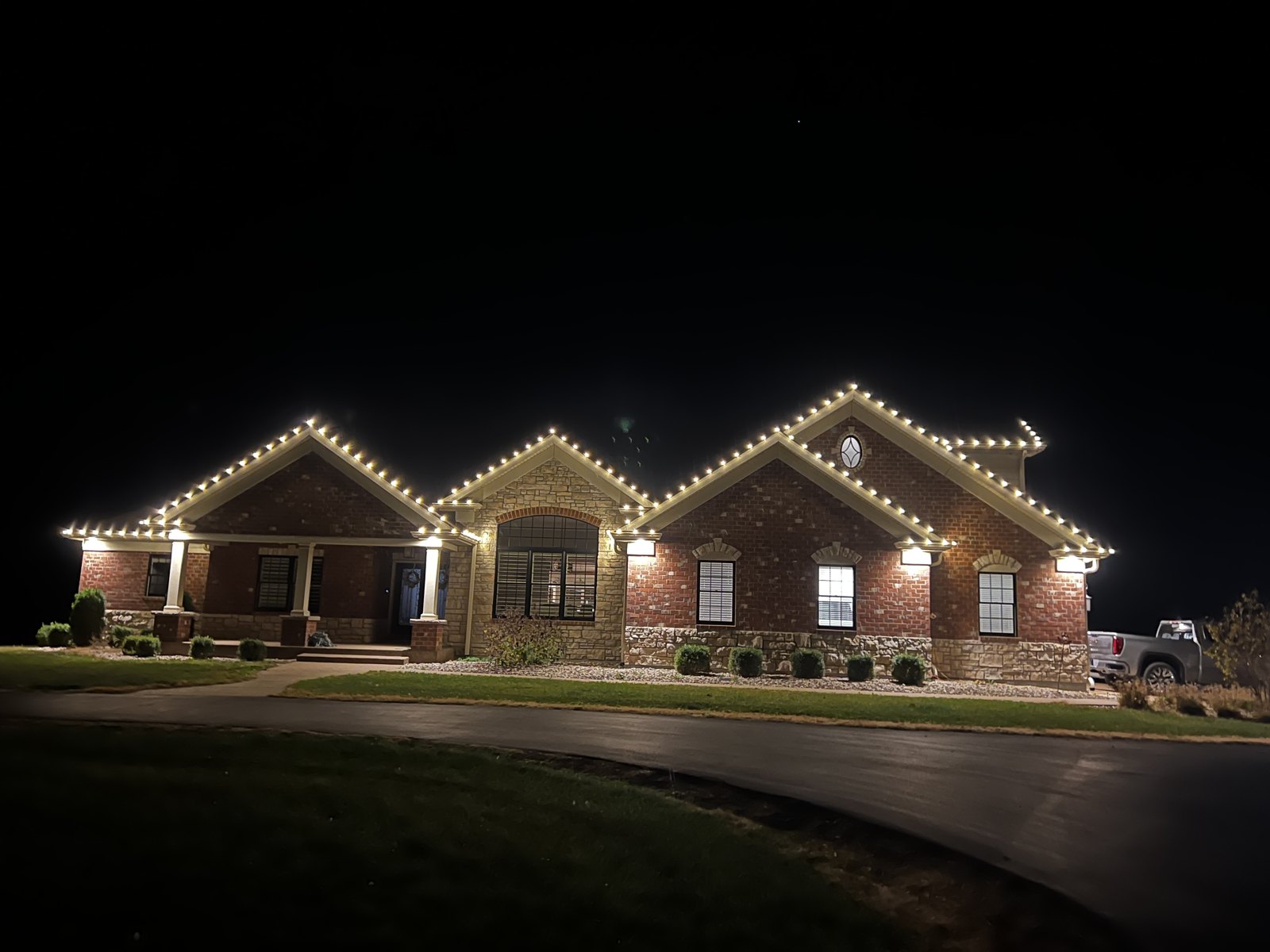 Warm white Christmas lighting around a brick home