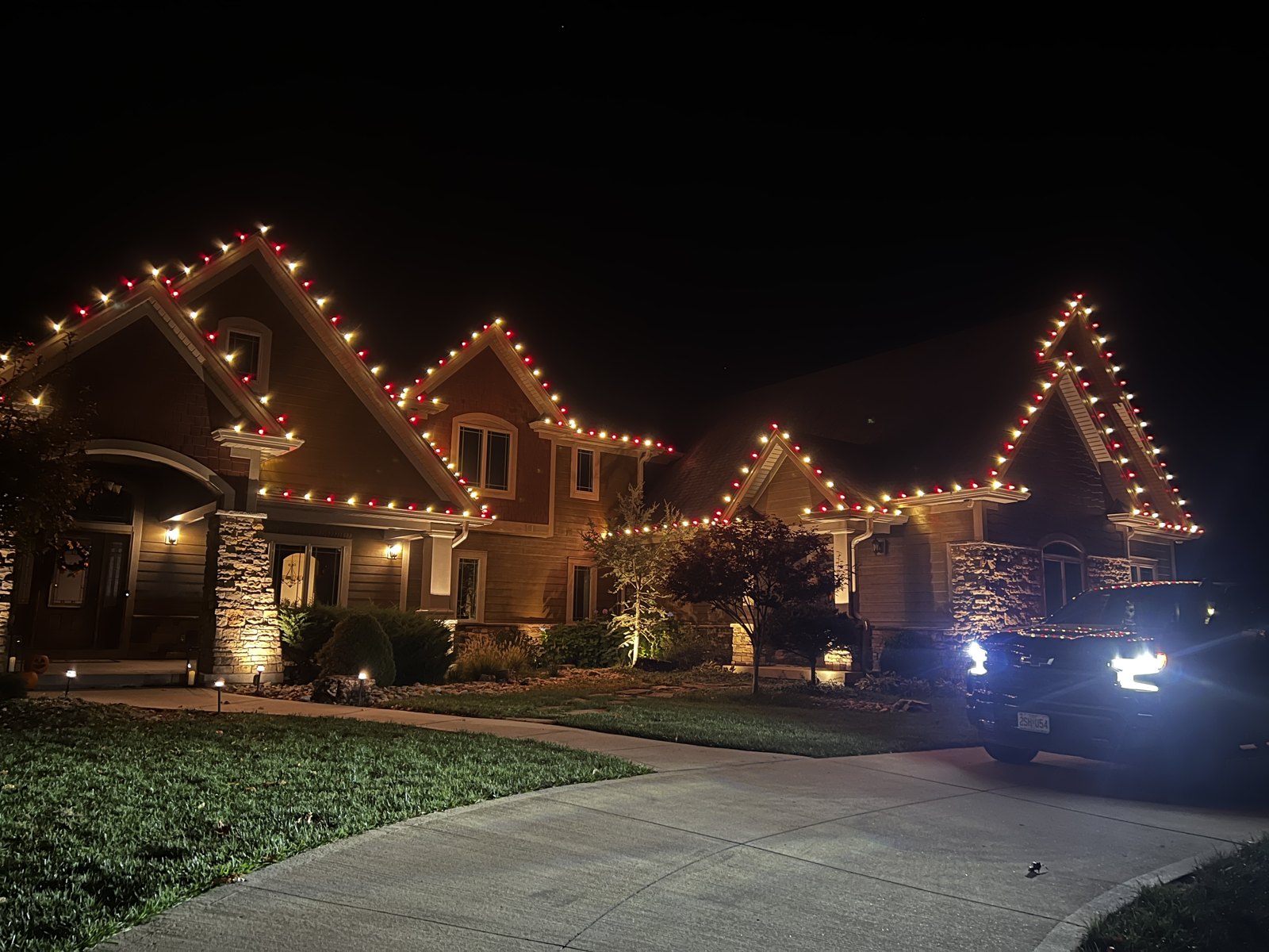 A home outlined in warm Christmas lights after dark