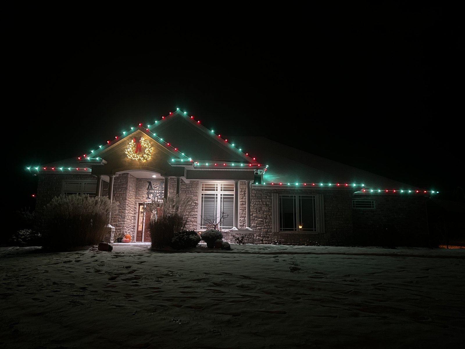 Green and white Christmas lighting on a two-story home